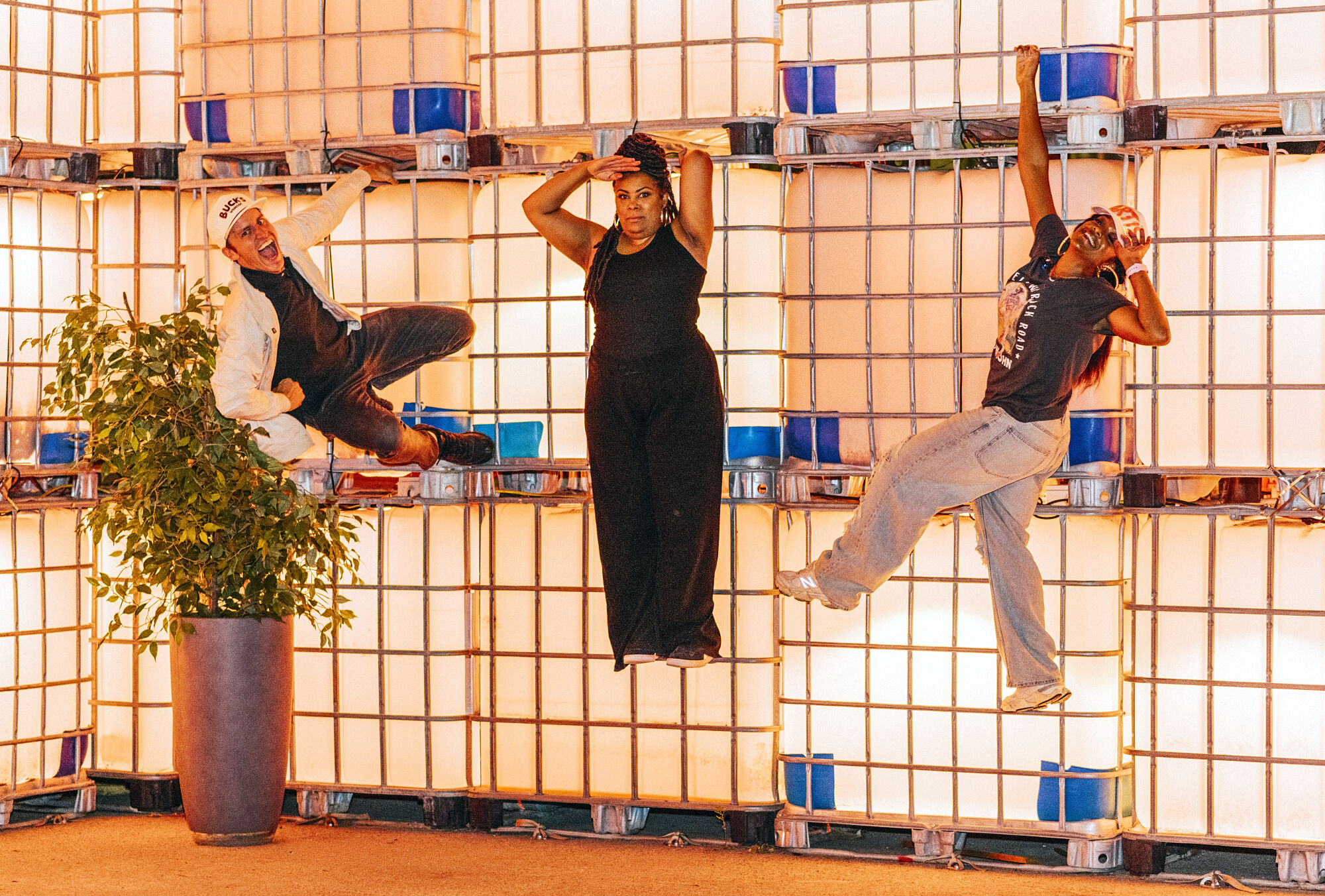 Three performers hanging off the side of a wall
