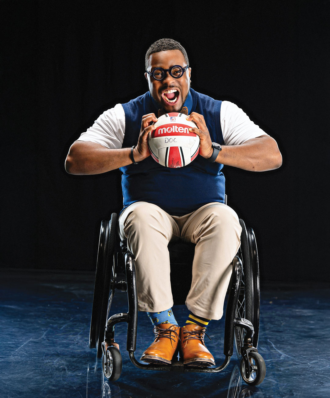 Dr. O in a wheelchair grasping a rugby ball