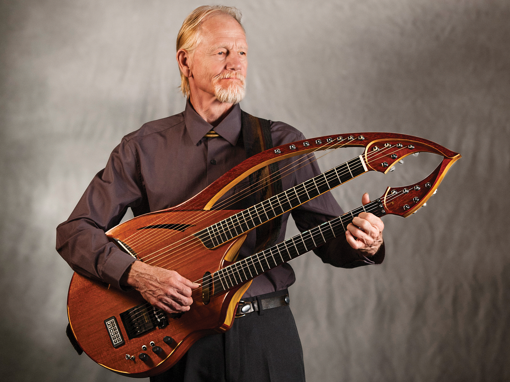 William Eaton holding a double-neck harp guitar