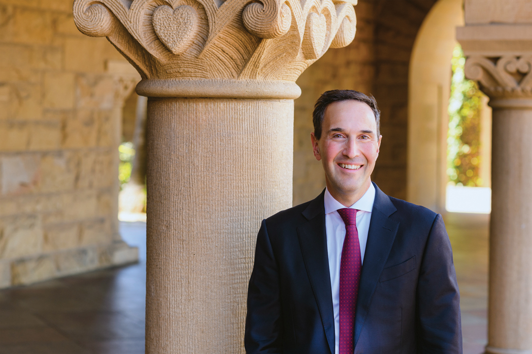 Jonathan Levin standing in the Quad in front of column archways