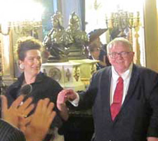 Webster, well-dressed, stands next to a woman inside of an exquisite, palace-like venue.