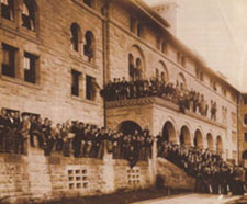 A photo of Encina hall with people tightly packed out front, on the stairs, and on the balcony.