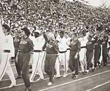 US and Soviet athletes marching side-by-side. One side wears dark uniforms labeled CCCP, the other wears white.