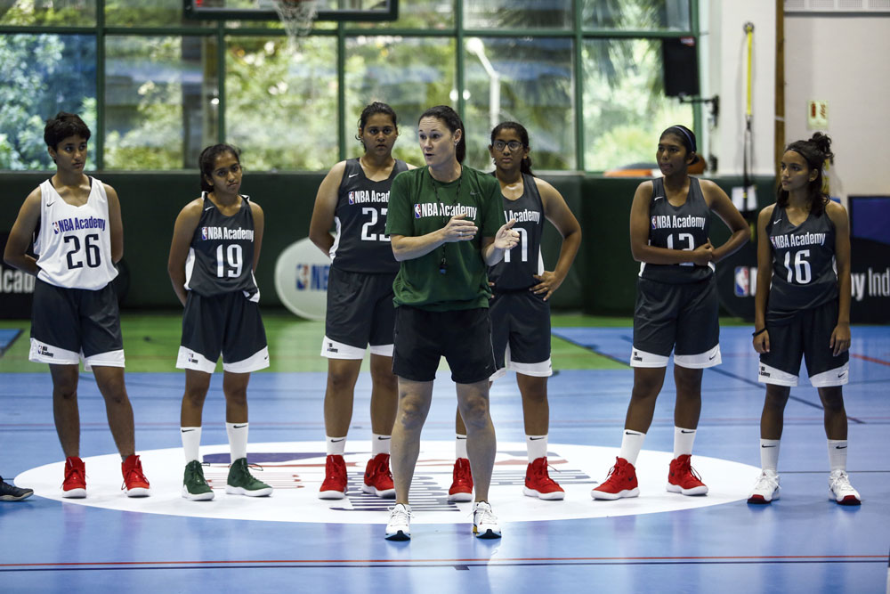 Jennifer Azzi, technical director of the NBA Academy Women’s Program, teaching her students on a basketball court.