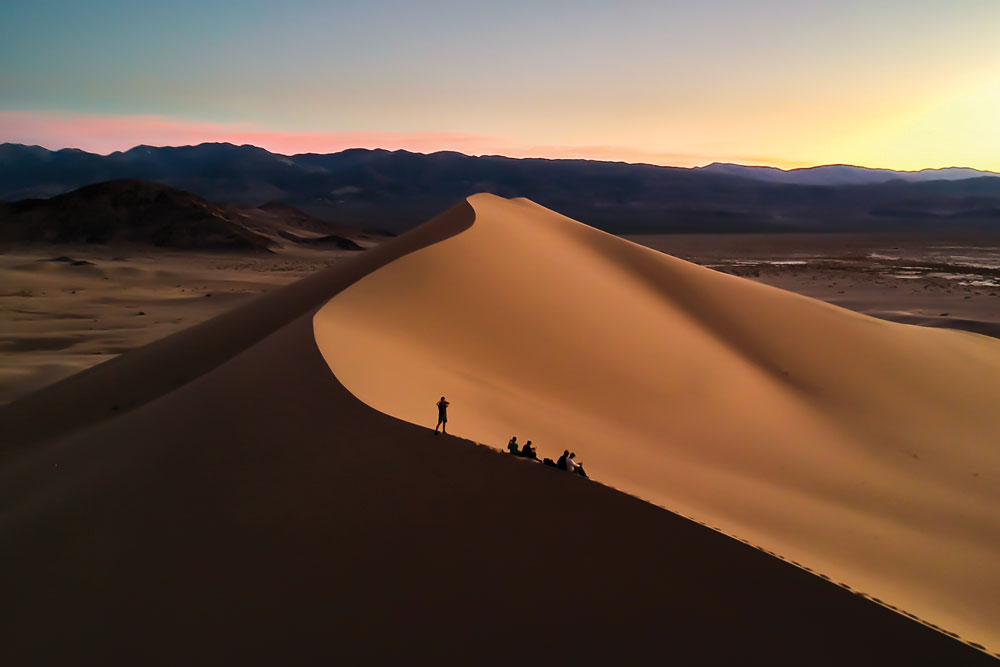 Students standing on top of a sand dune in at sunset.