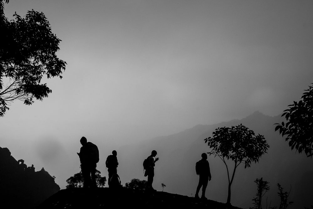 Black and white photo of students hiking through a rain forest in Hawaii with mist and trees.