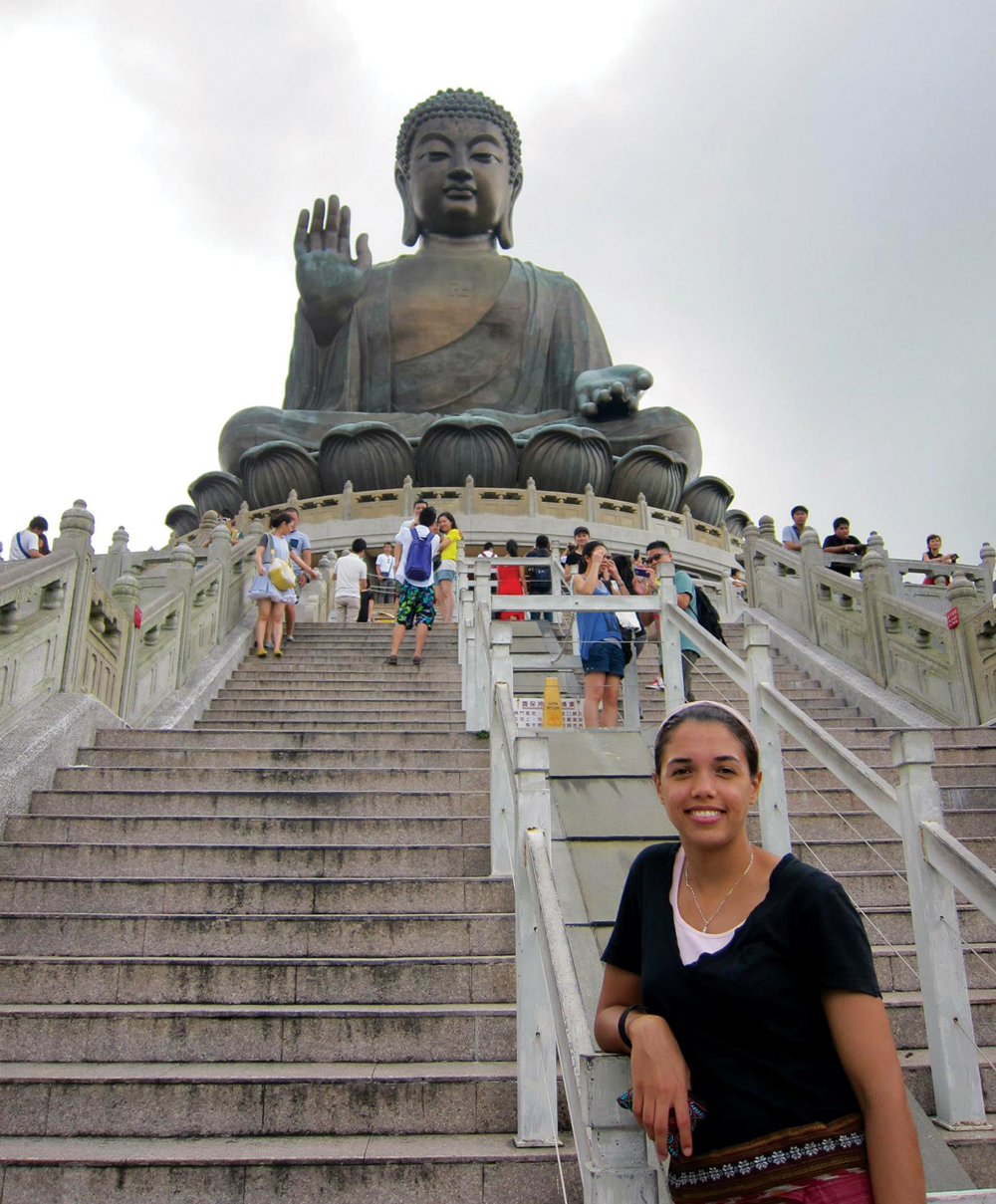 Amber Moore standing at the bottom of the steps below a giant statue in Hong Kong