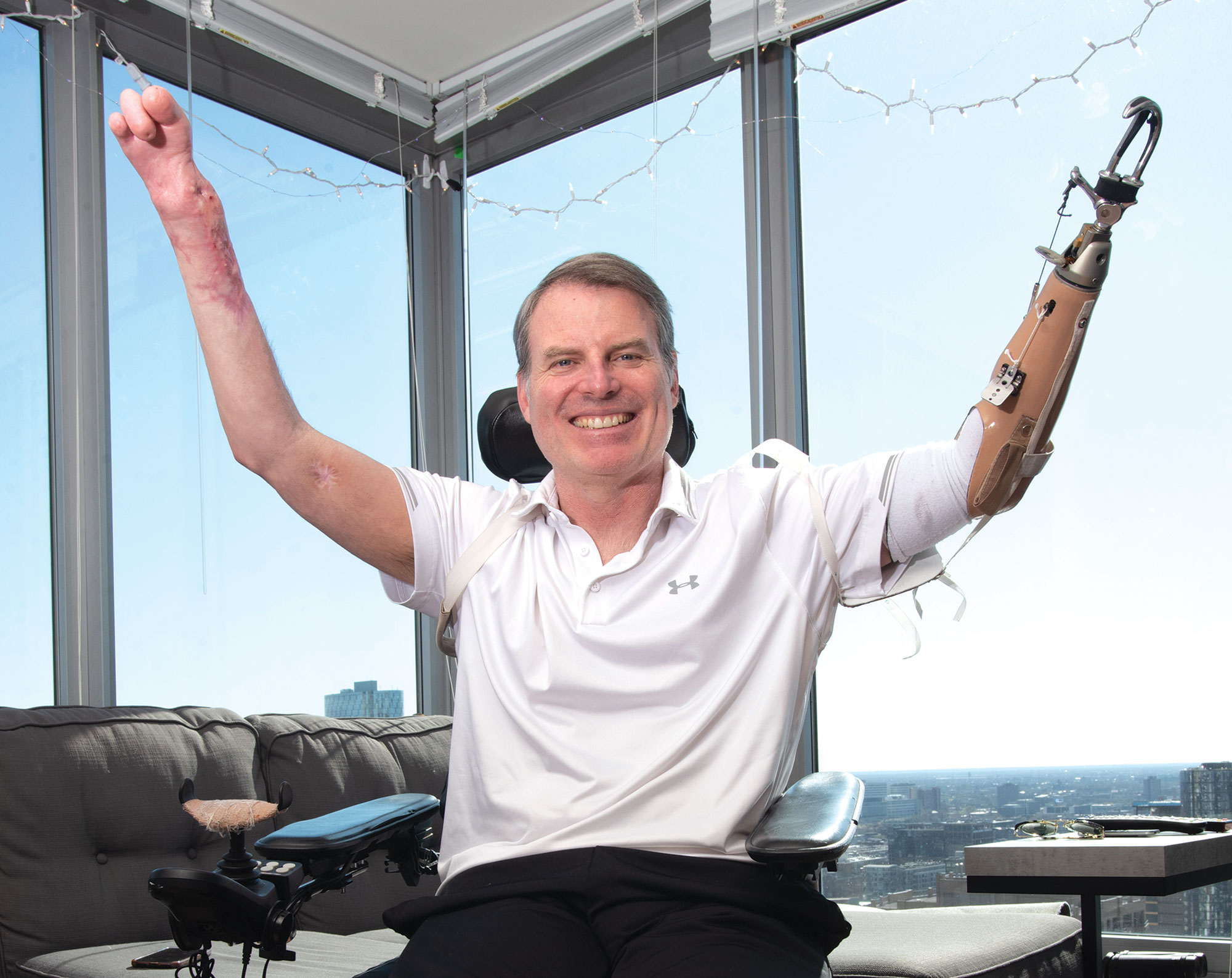 Marty Hartigan triumphantly raising his hands over his head in front of large window