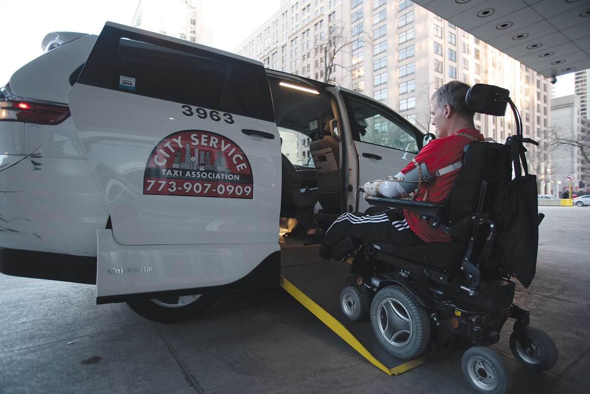 Marty Hartigan driving electric wheelchair inside a taxi