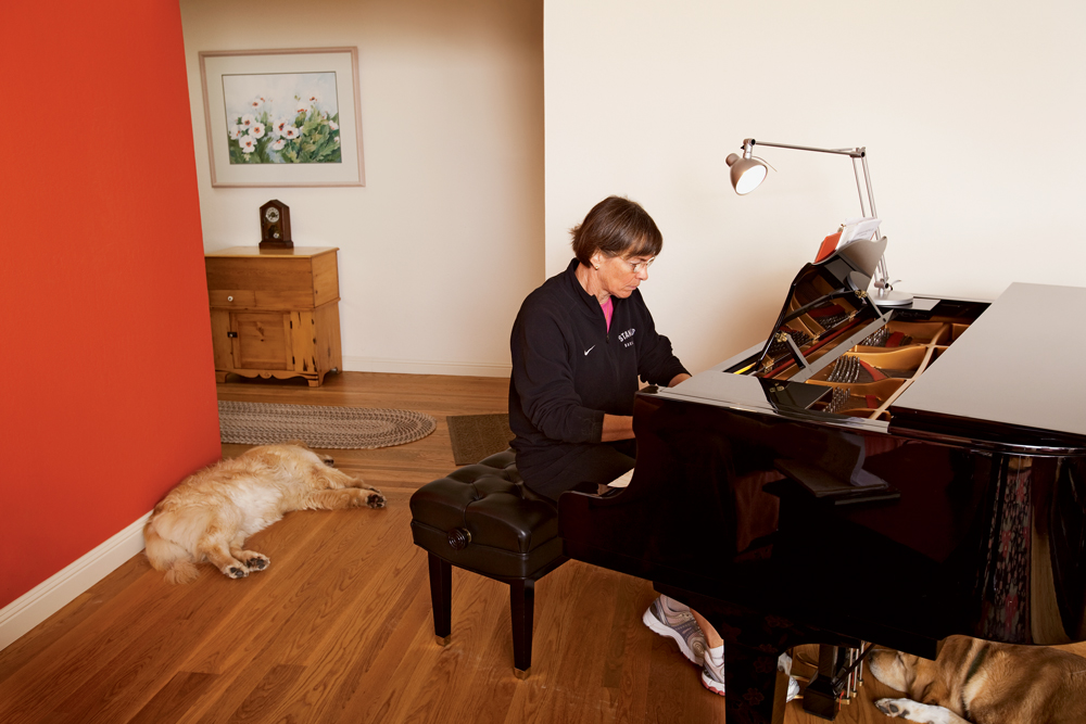 VanDerveer playing her piano with her dogs asleep on the floor