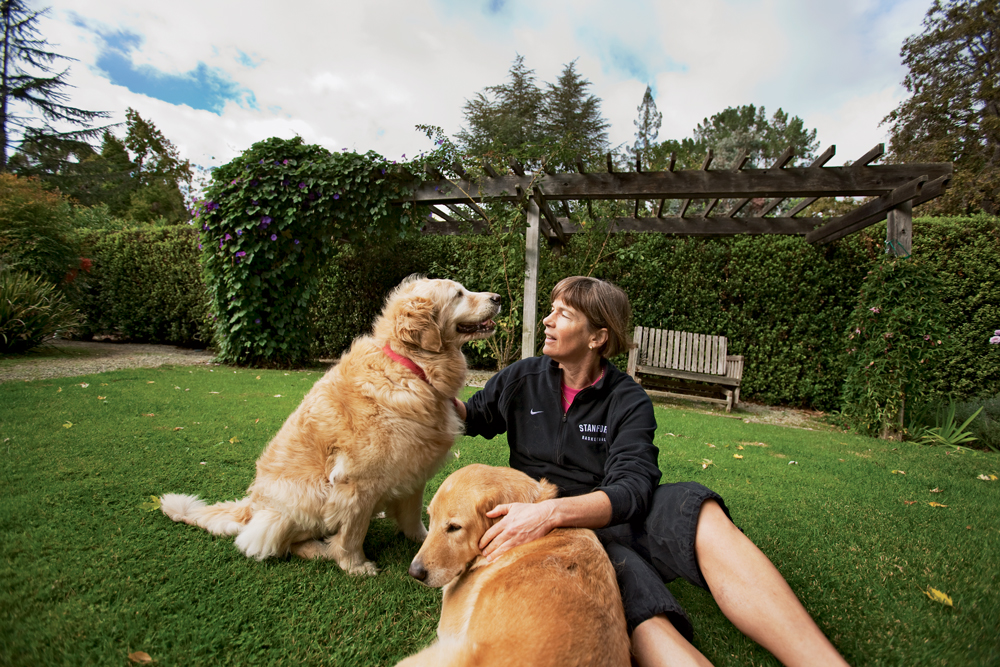 VanDerveer on the lawn petting her dogs