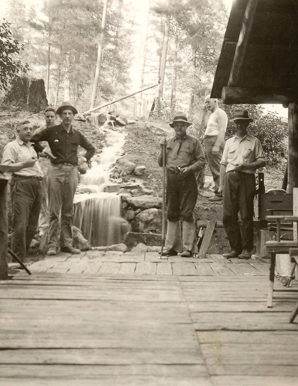 Six men, including Herbert Hoover and Ray Lyman Wilbur stand on the deck of an old cabin.