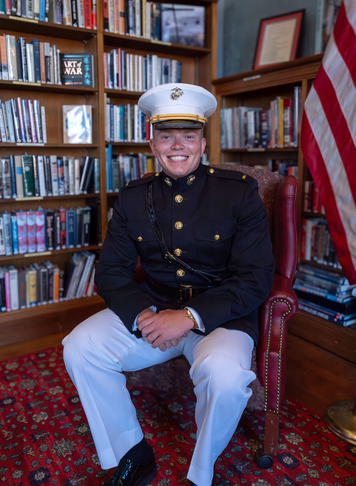 Chernik in his Dress Blue uniform, seated in front of bookshelves.