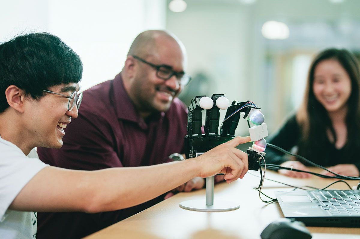 Kennedy and team looking at a robotic fingertip.
