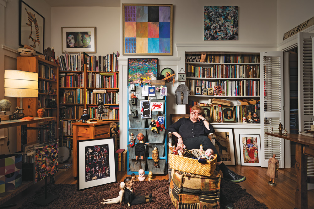 Terry Castle sitting in a room amongst books and dolls and art