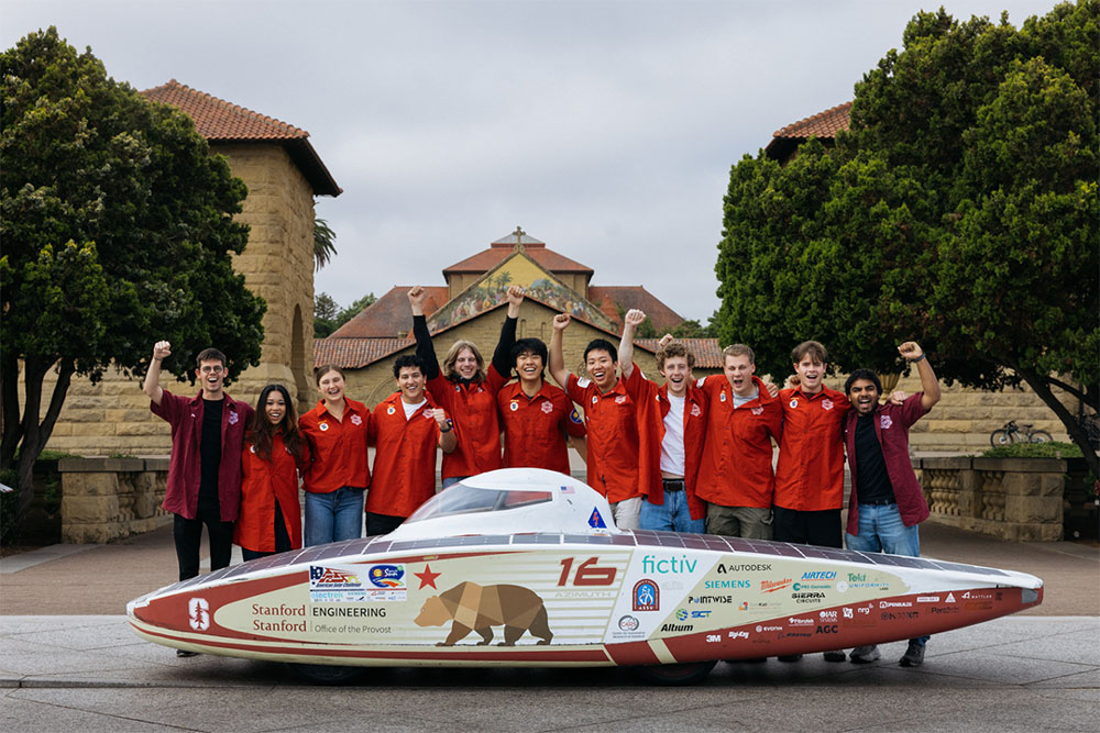 A group of students standing behind the solar car