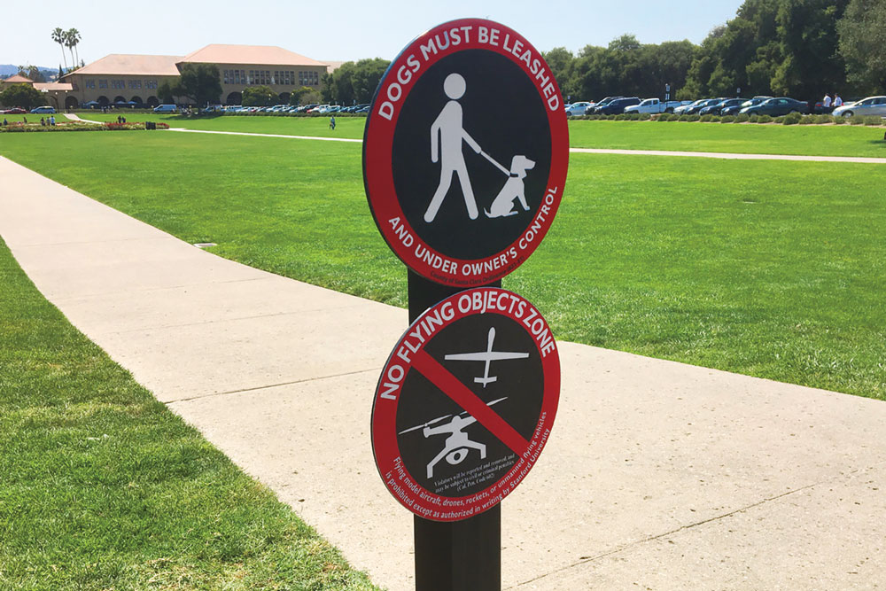 Two round signs: one says dogs must be leashed and the other says no flying objects zone