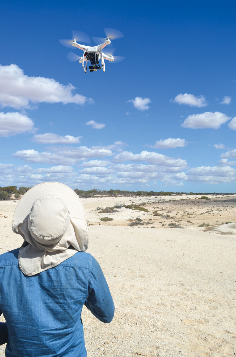 A person flying a drone over sand
