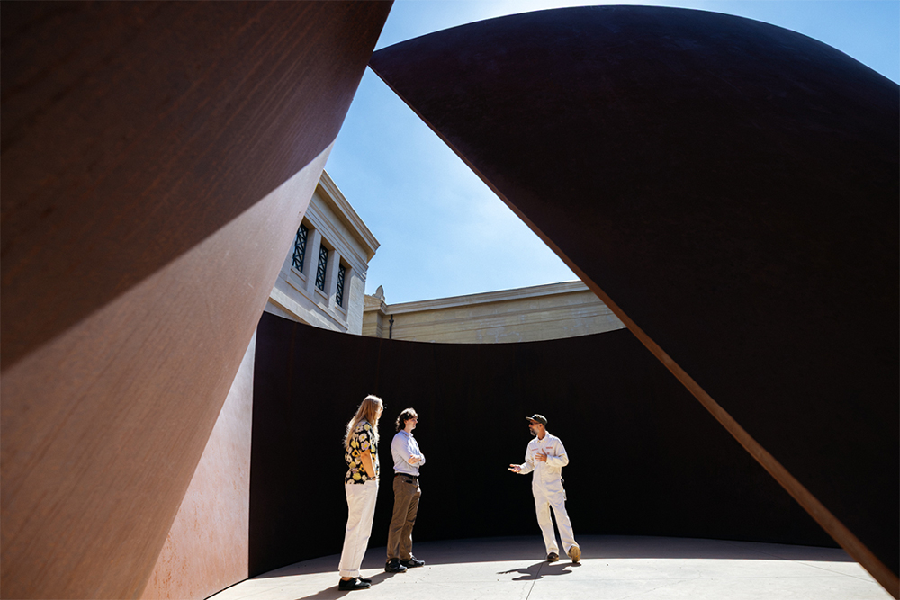 Mark Shunney and two other people standing at the steel sculpture, Sequence