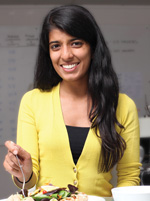 Ooshma Garg sitting behind a plate of food.
