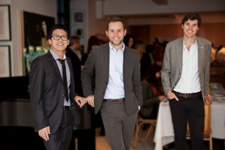 Ferguson, Marshall, and Tang stand together in a restaurant. They're all wearing suits.